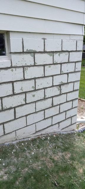 Repaired and sealed block foundation corner beside home siding in Omaha