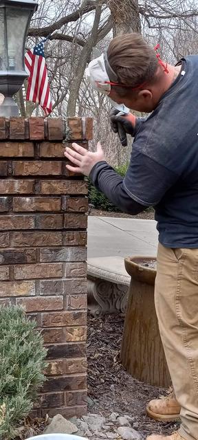 Mason hand-laying brick on a rebuilt pillar in Omaha