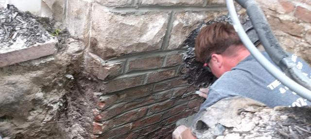 Mason rebuilding a brick and stone foundation corner on an Omaha home