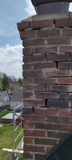 Corner of a historic Omaha chimney showing open joints and loose brick before tuckpointing