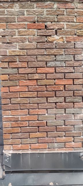 Chimney face with washed-out mortar joints before tuckpointing in Omaha
