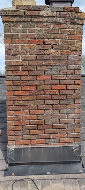 Historic brick chimney in Omaha before tuckpointing, with crumbling crown and recessed mortar joints